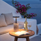 Petra encendida en una mesa de teca de una terraza mediterránea al anochecer